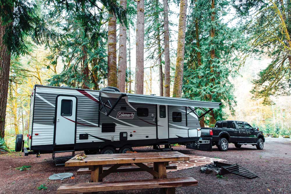 A travel trailer and truck in camp A travel trailer and truck in a forested campsite