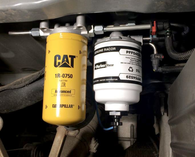 Yellow CAT fuel filter and white factory fuel/water separator installed in engine.