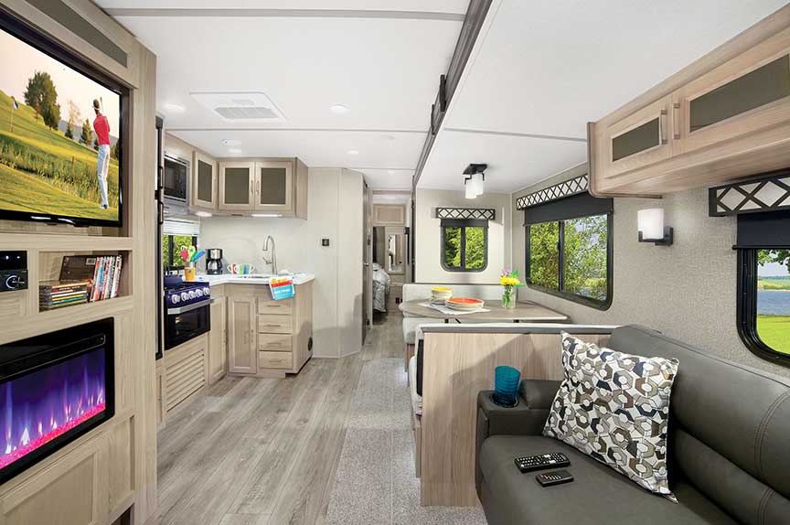 Main living area of Coachmen Freedom Express 326BHDS Liberty Edition View from back to front in the gray-hued interior with an electric fireplace and flat-screen TV on the left.