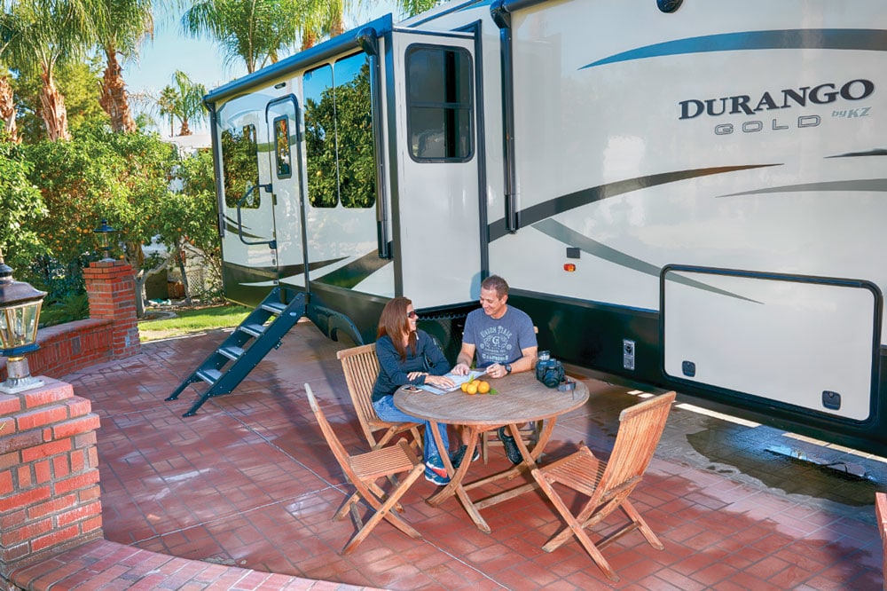 Couple sitting at outdoor table next to large Durango RV
