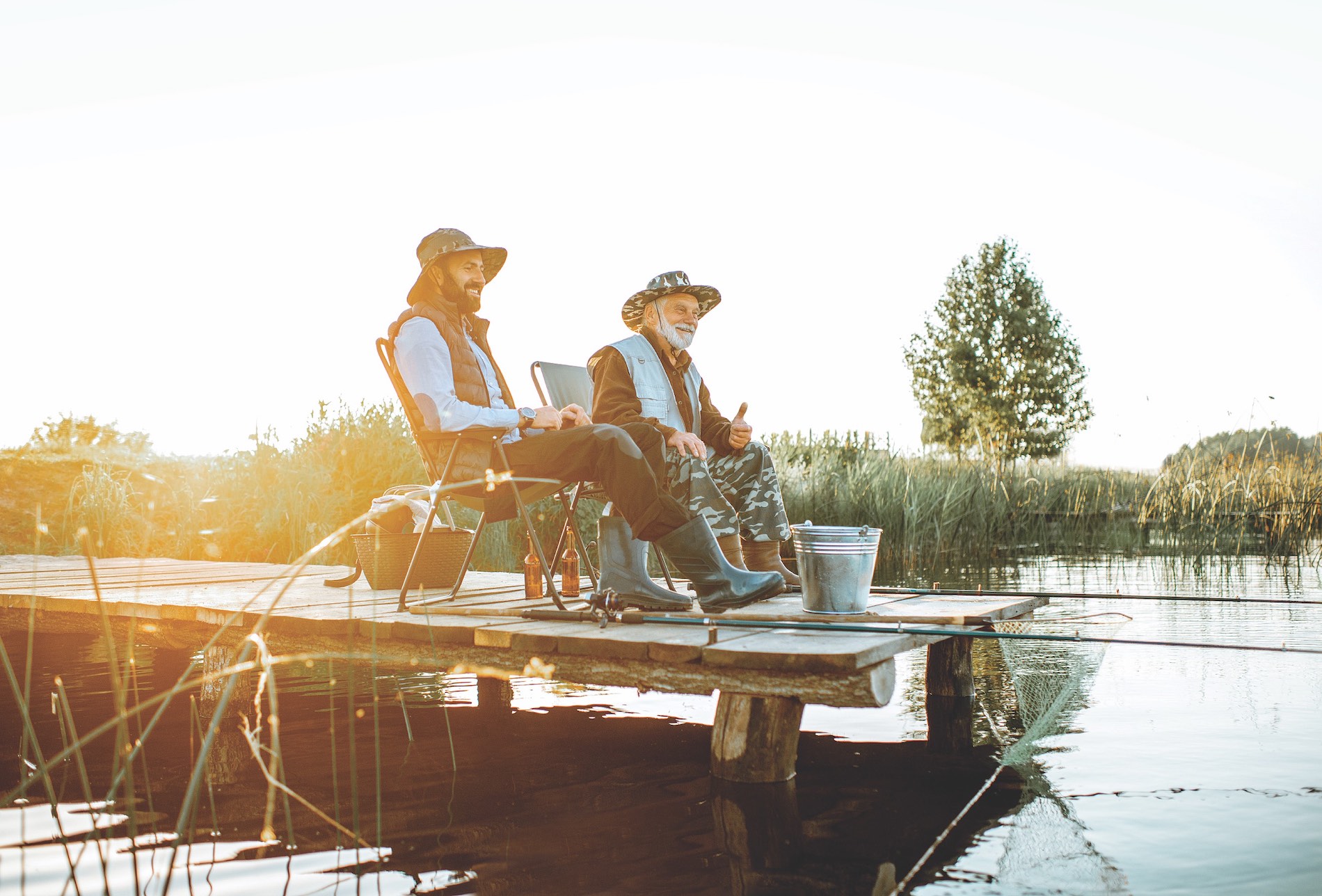 Two men sitting fishing and having a beer