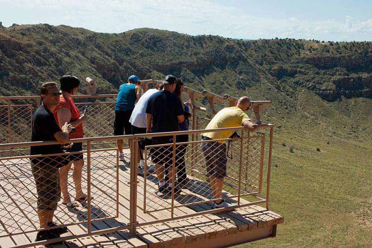 Meteor Crater — sightseers looking into a deep crater with telescopes.