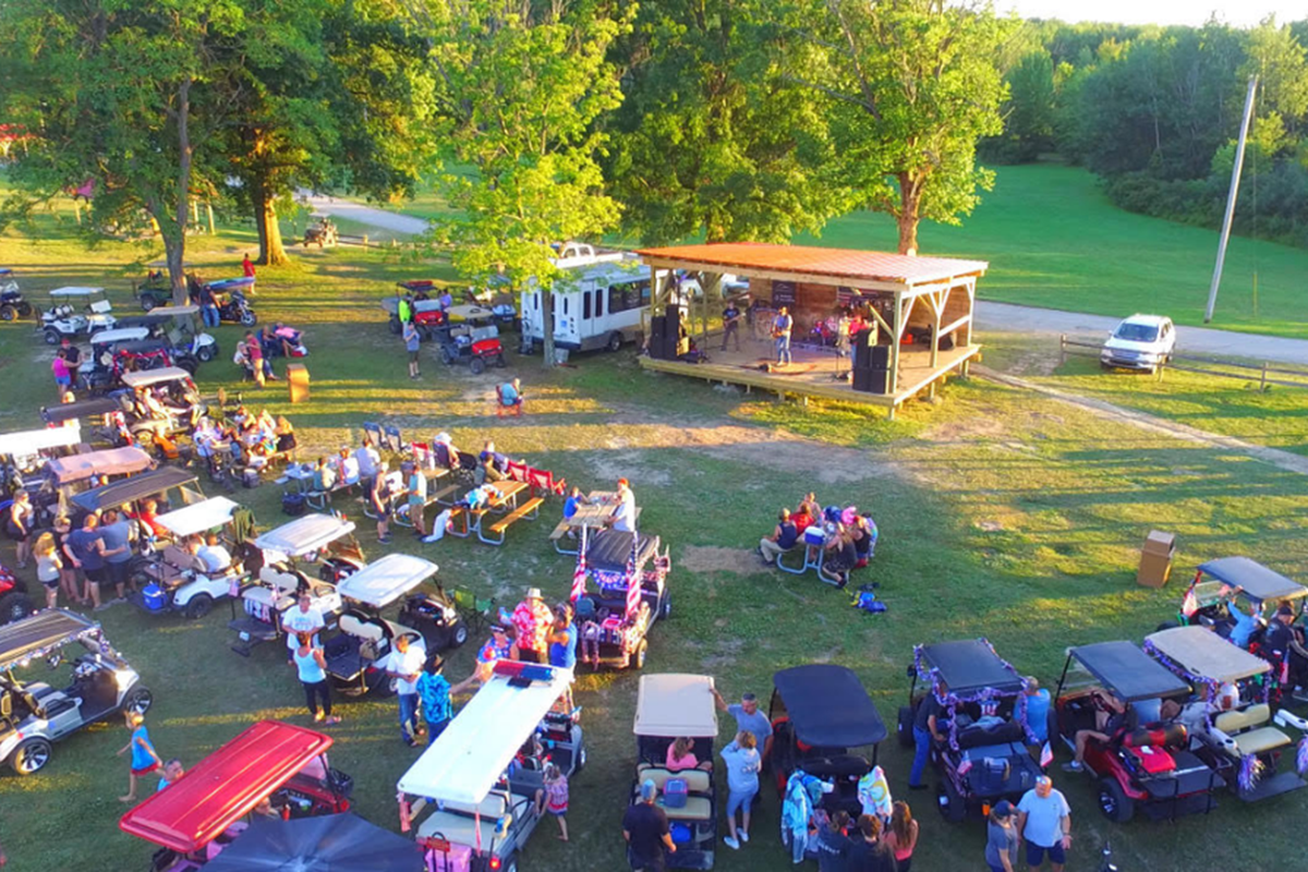 Campers form a semi-circle around a concert stage.