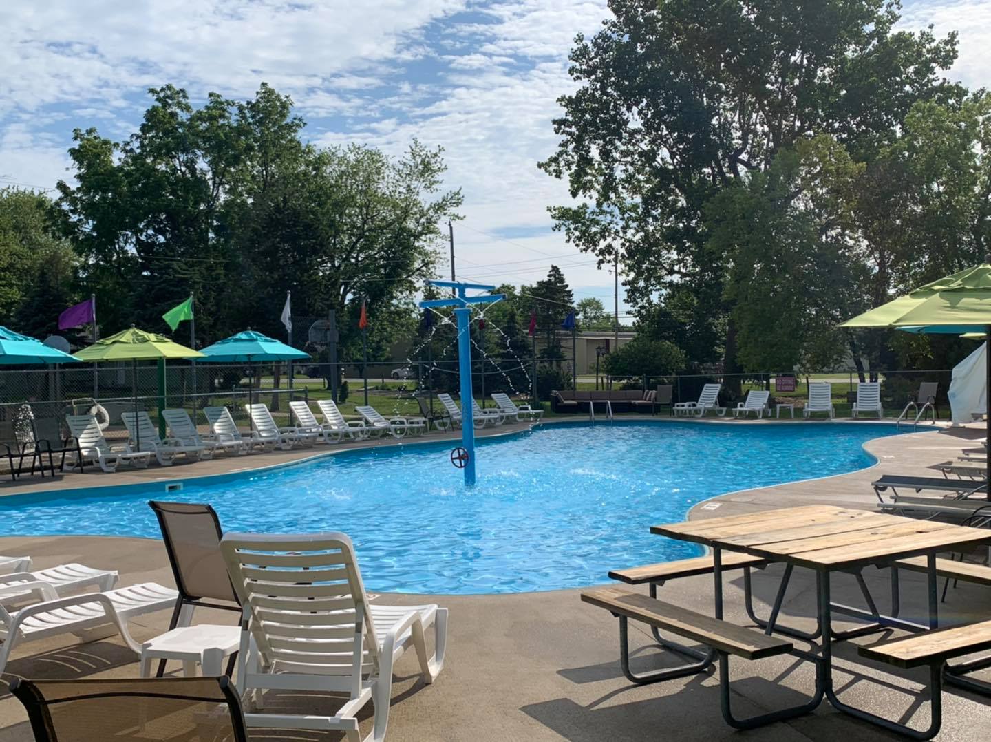 Swimming pool surrounded by chaise lounges and tables.