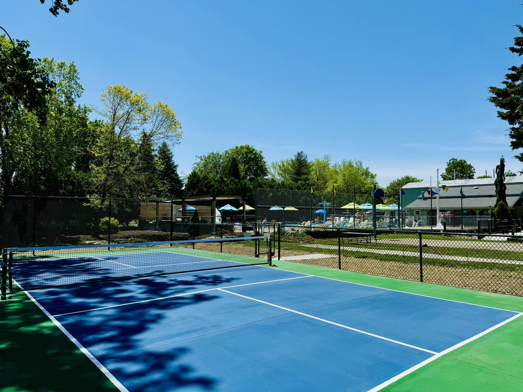 Blue pickleball court partly shaded.