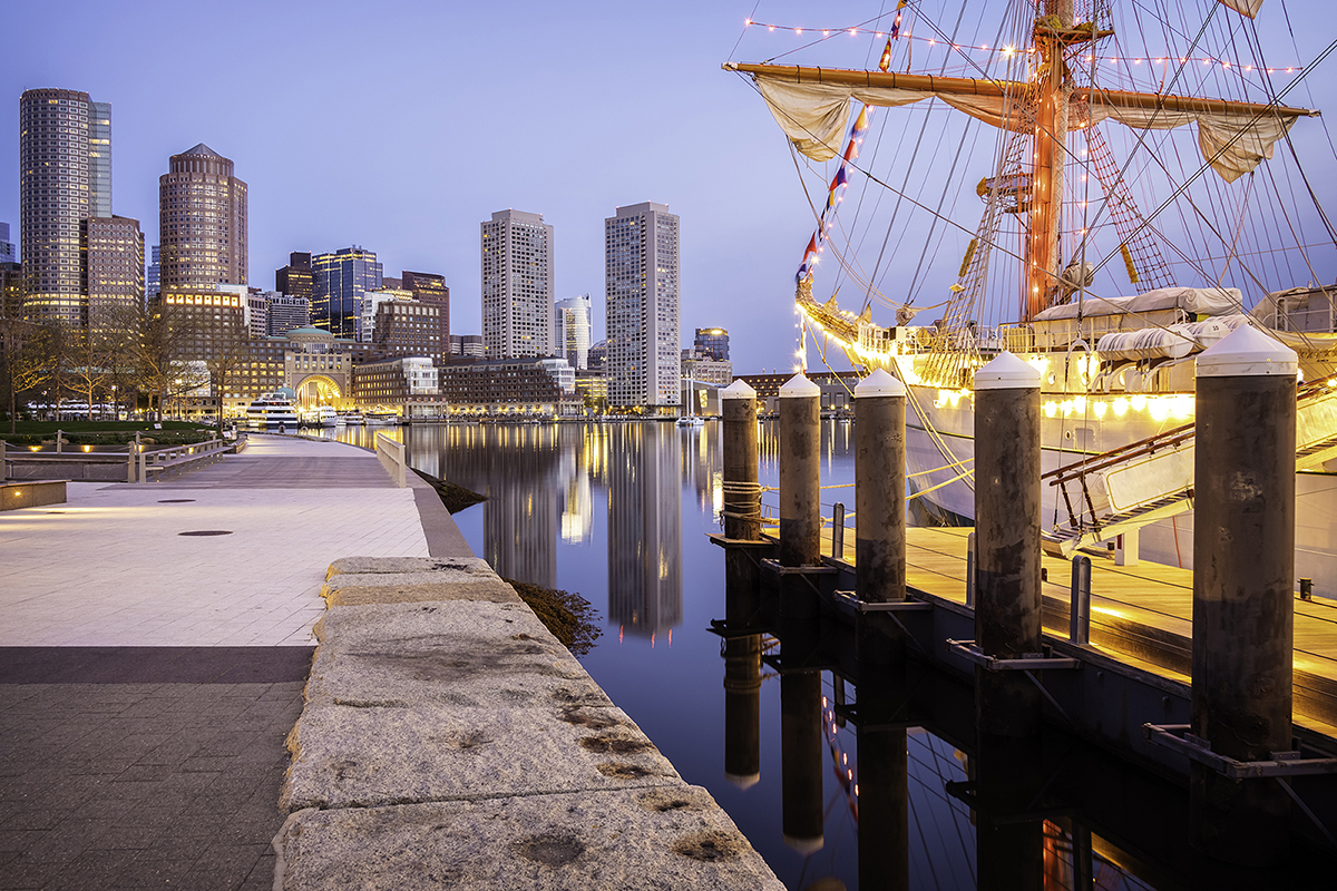 Centuries-old sailing ship moored at harbor of major city.