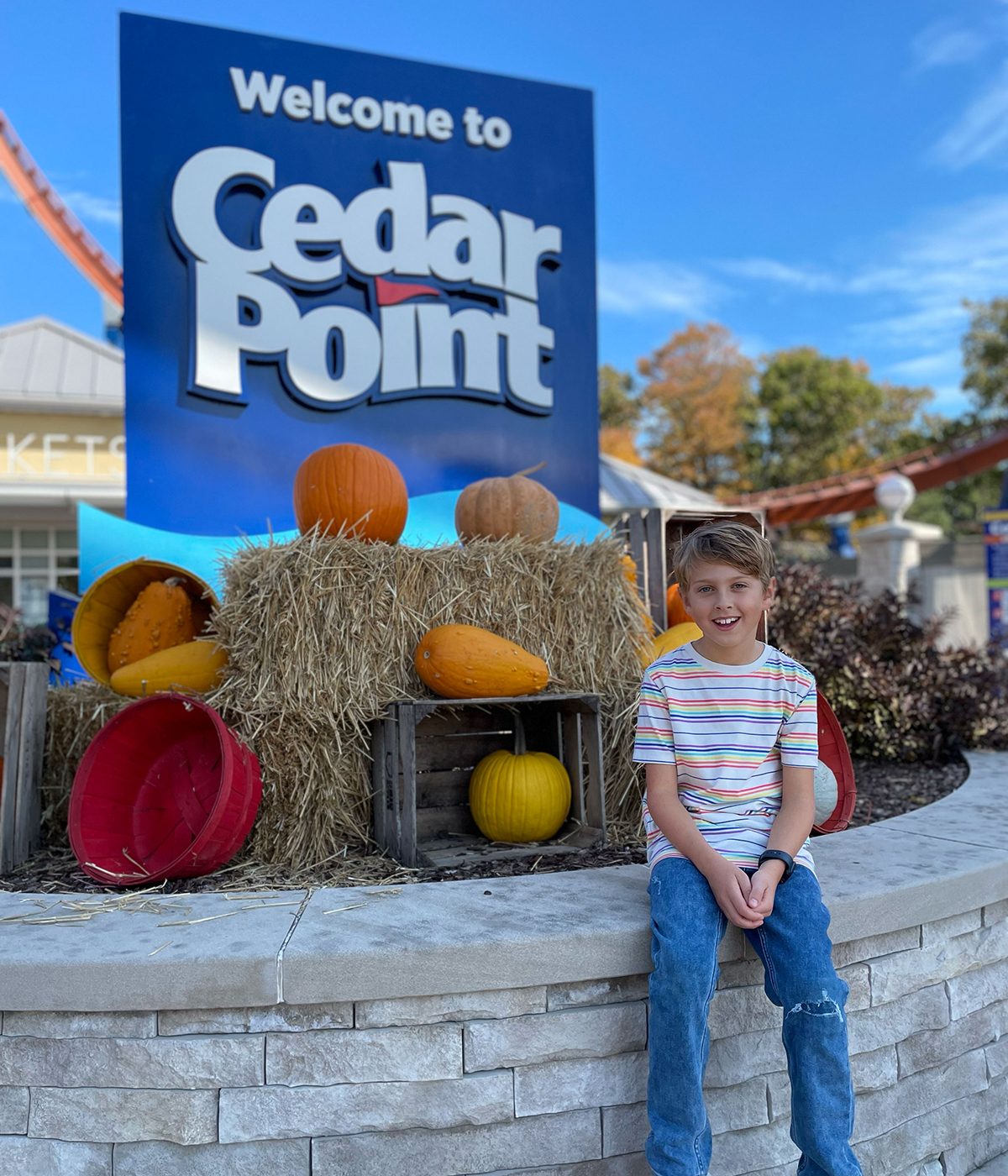 Kid sitting in front of Cedar Point sign.